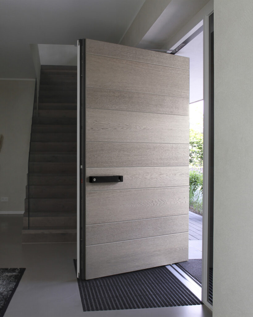 Eine große Holzhaustür öffnet sich nach draußen mit Treppen im Hintergrund