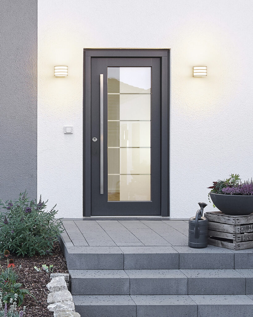 Eine moderne graue Haustür mit Glas, seitlich von Beleuchtung eingerahmt