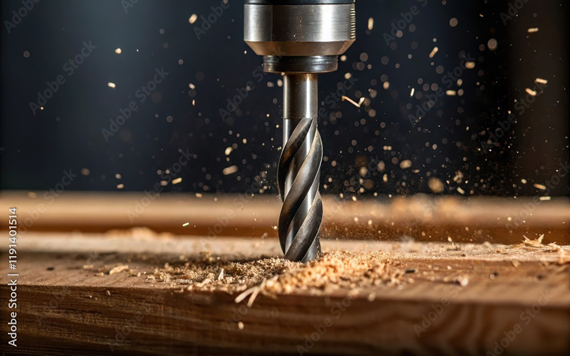 Eine Bohrmaschine schafft Späne auf einem Holzbrett in Nahaufnahme.