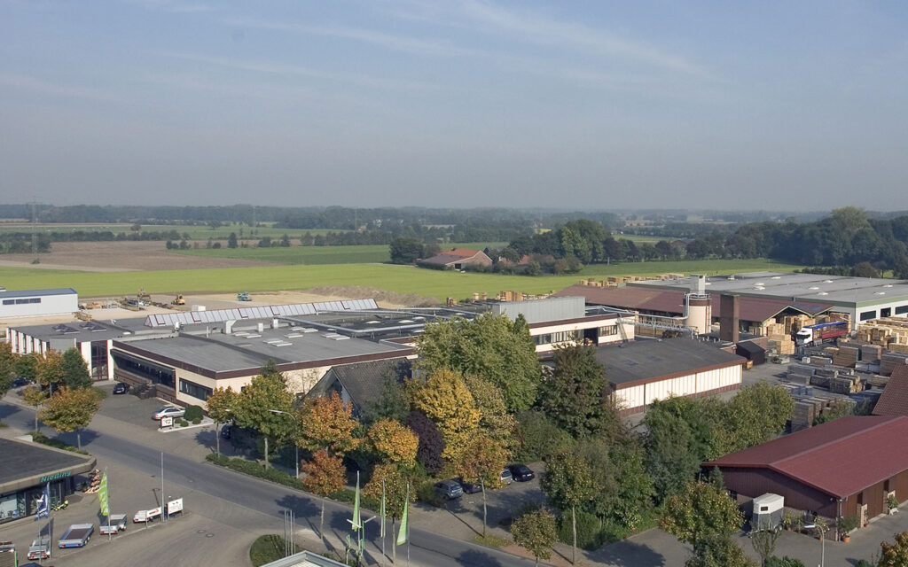 Luftaufnahme eines großen Industriekomplexes mit Feldern im Hintergrund.