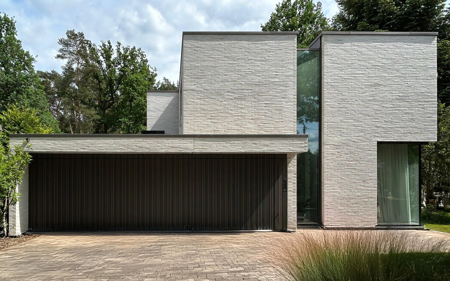Modernes, zweistöckiges Haus aus weißem Ziegelstein mit großen Glasfenstern.