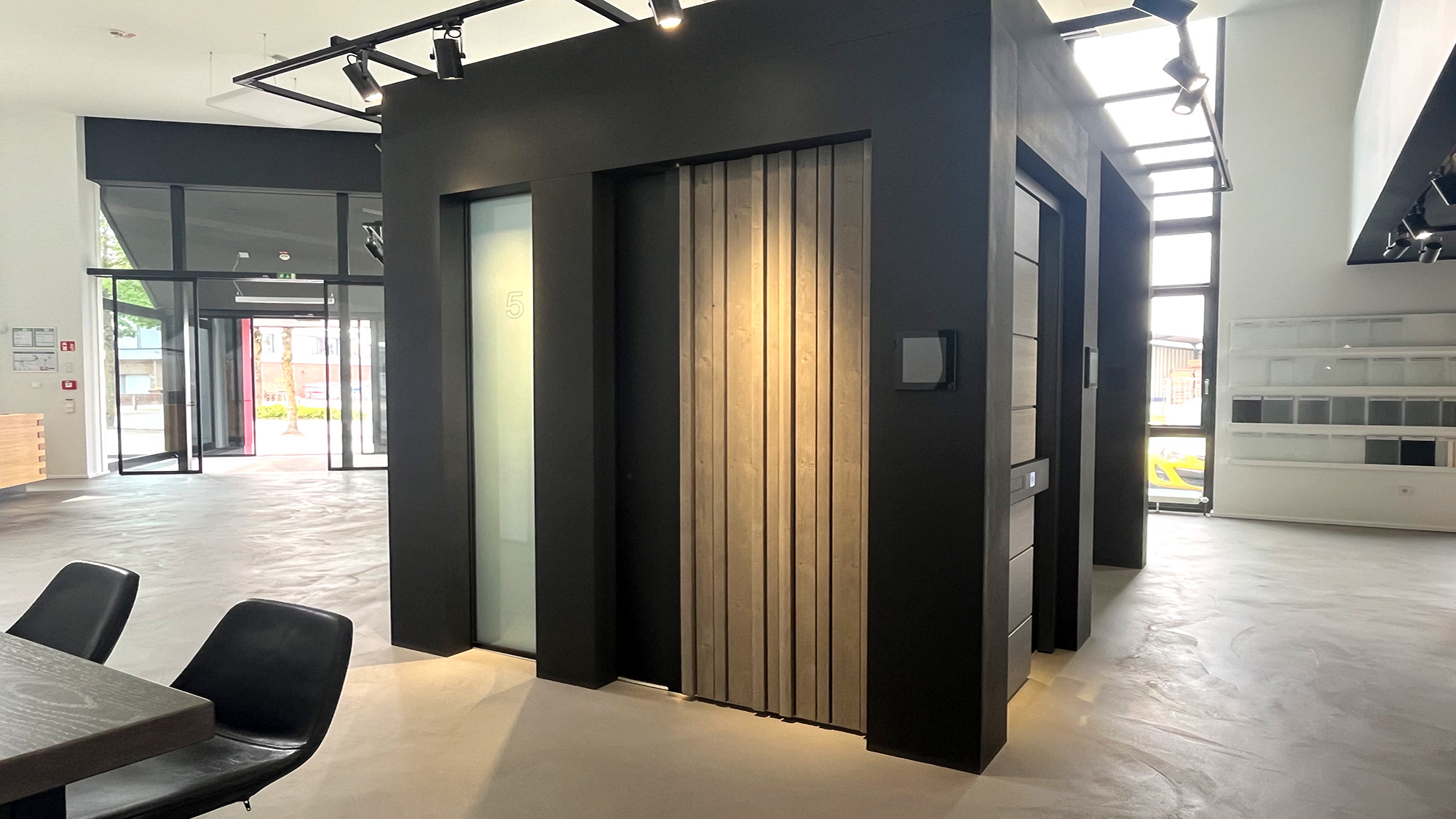 Moderner schwarzer Innenraum mit Holzlamellenwand und Glasfront, ruhig