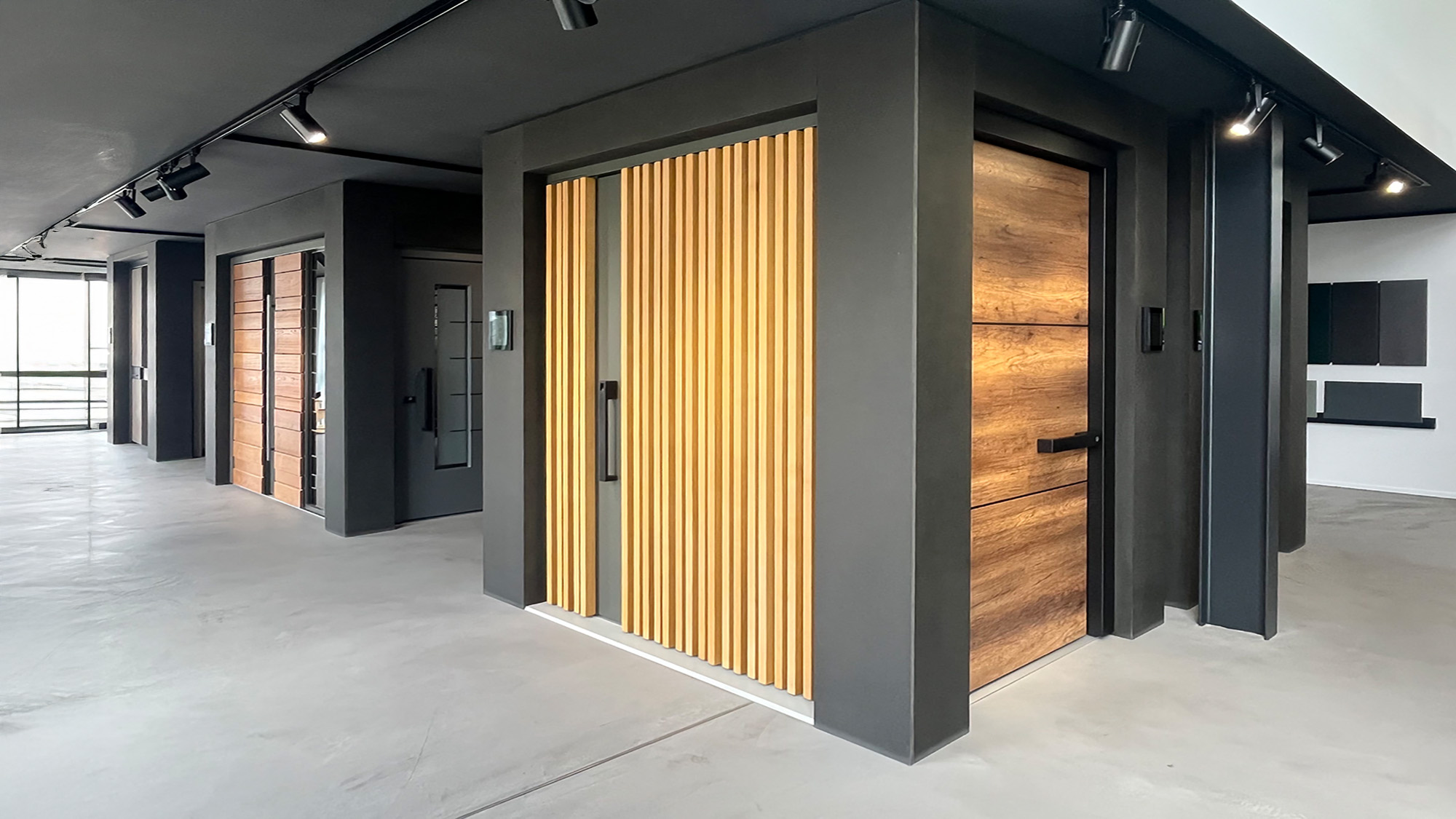 Moderner Showroom mit grauen Wanden, Holzlamellentur und Holzschiebetur, hell