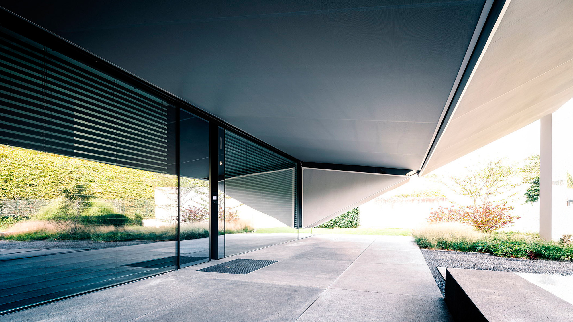 Moderner Gebäudeeingang in Grau und Schwarz mit Glasfront und Lamellen