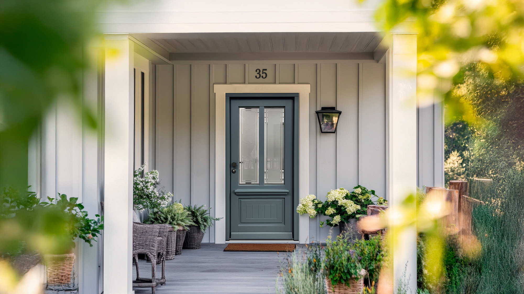 Graue Veranda mit blauer Tür, Hausnummer 35, Blumen und Laterne, ruhig